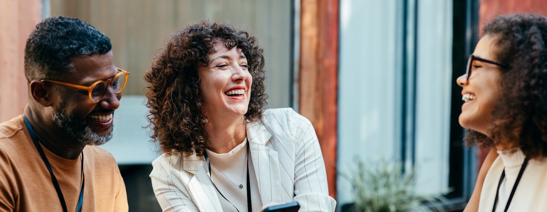 three people laughing and holding a phone